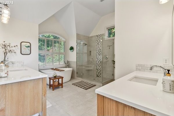 bathroom featuring plus walk in shower, vanity, and lofted ceiling