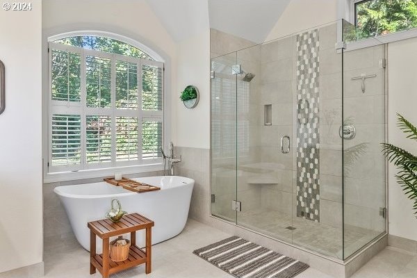 bathroom featuring tile walls, plenty of natural light, lofted ceiling, and plus walk in shower