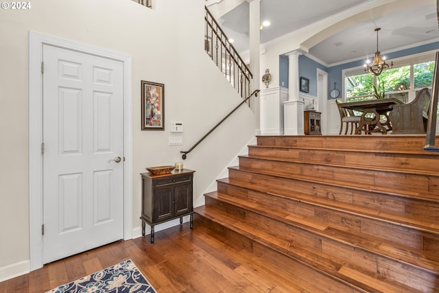 stairs with ornamental molding, wood-type flooring, and decorative columns