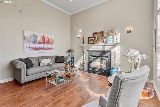 living room featuring a towering ceiling, a fireplace, hardwood / wood-style flooring, and crown molding