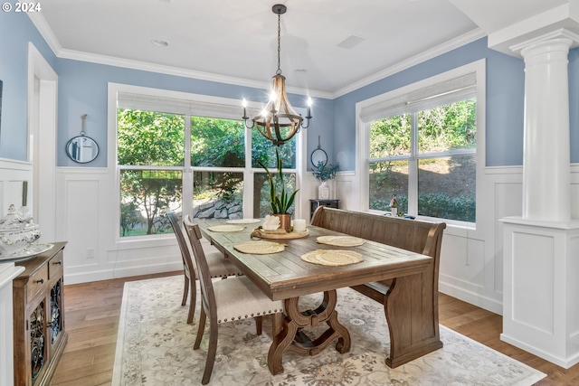 dining area with decorative columns, a notable chandelier, light hardwood / wood-style floors, and crown molding