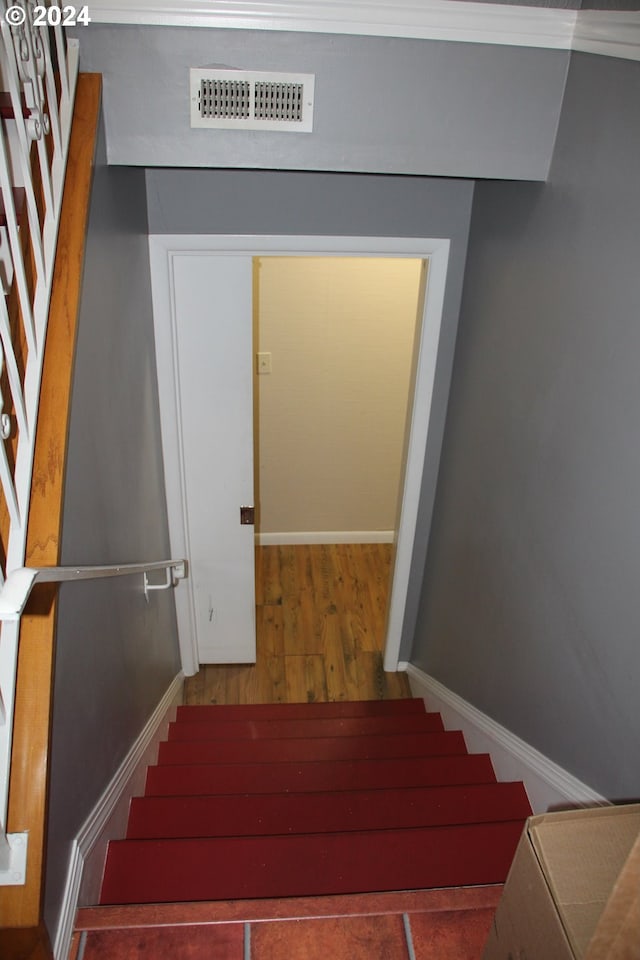 stairway with crown molding and hardwood / wood-style flooring