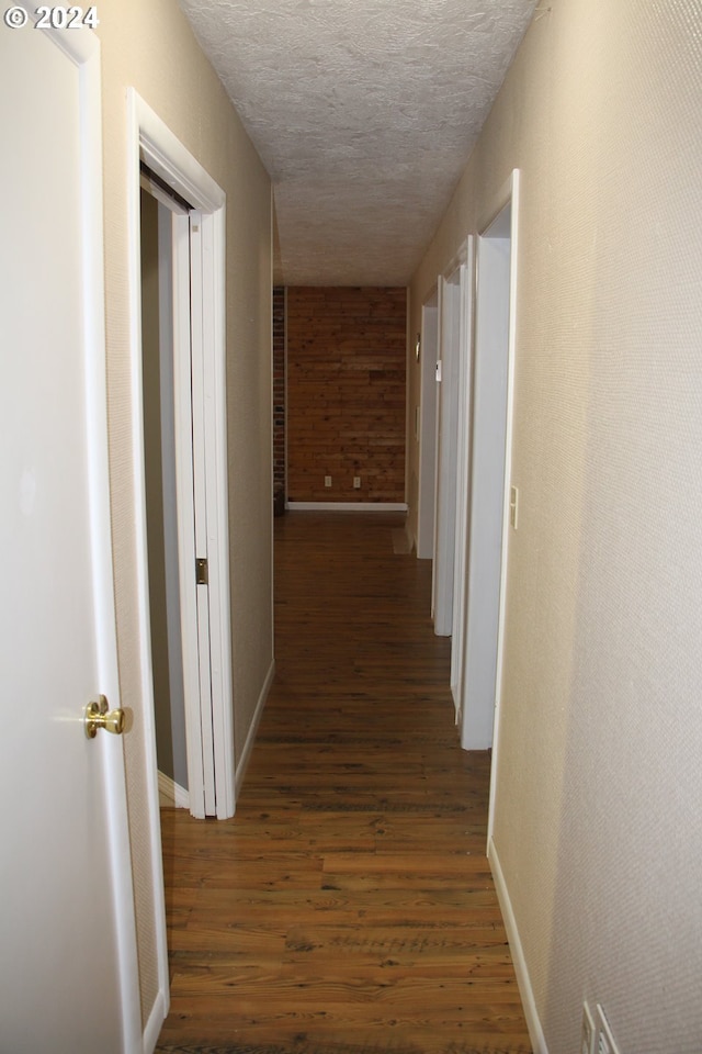 hallway featuring a textured ceiling and dark hardwood / wood-style floors