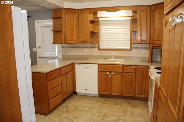 kitchen featuring kitchen peninsula, decorative backsplash, sink, and white appliances