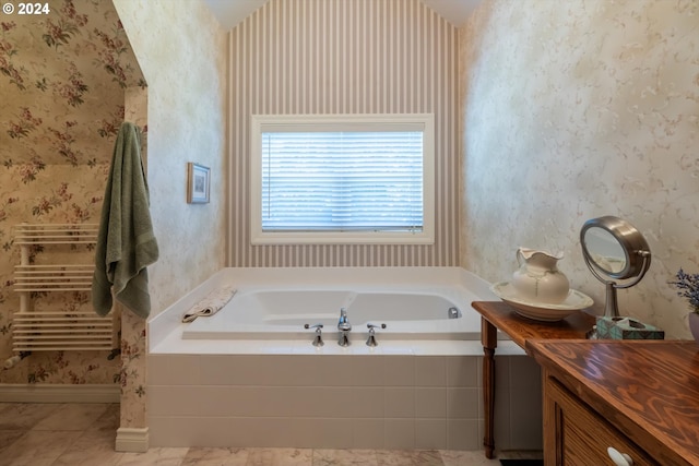 bathroom with tile patterned flooring, vanity, and tiled tub