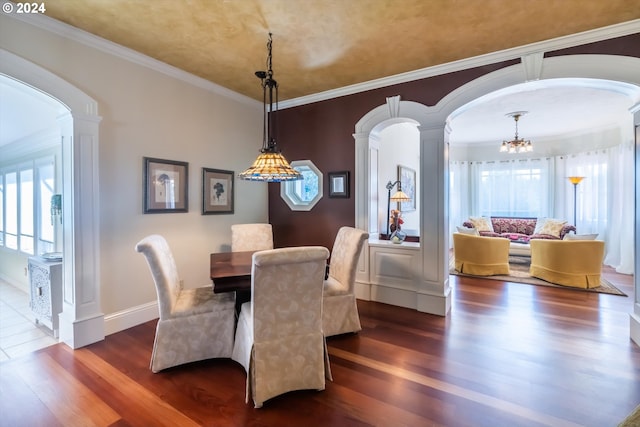 dining area featuring ornate columns, a notable chandelier, dark hardwood / wood-style floors, and ornamental molding