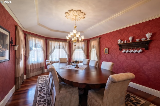 dining space featuring a tray ceiling, ornamental molding, dark wood-type flooring, and an inviting chandelier