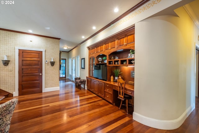 bar featuring crown molding, built in desk, and dark wood-type flooring