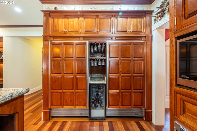 kitchen featuring hardwood / wood-style flooring, light stone counters, and ornamental molding