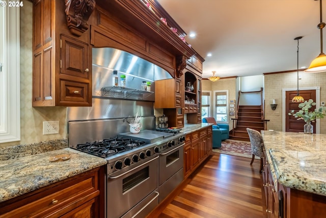 kitchen featuring light stone countertops, range hood, double oven range, and decorative light fixtures