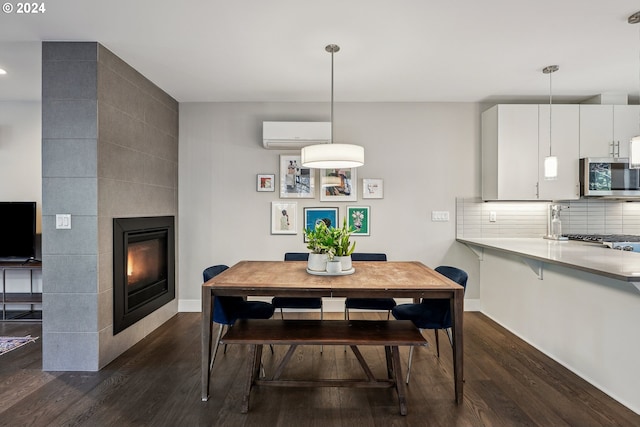 dining space featuring dark hardwood / wood-style floors, a tile fireplace, and a wall mounted AC