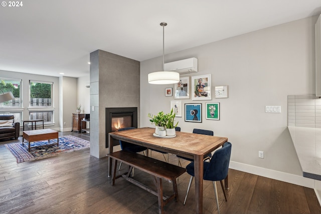 dining area featuring a wall mounted AC, a tile fireplace, and hardwood / wood-style flooring