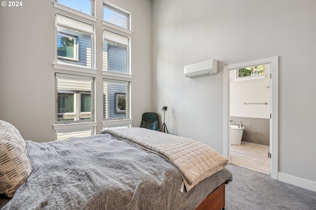 carpeted bedroom featuring an AC wall unit, ensuite bath, and a high ceiling