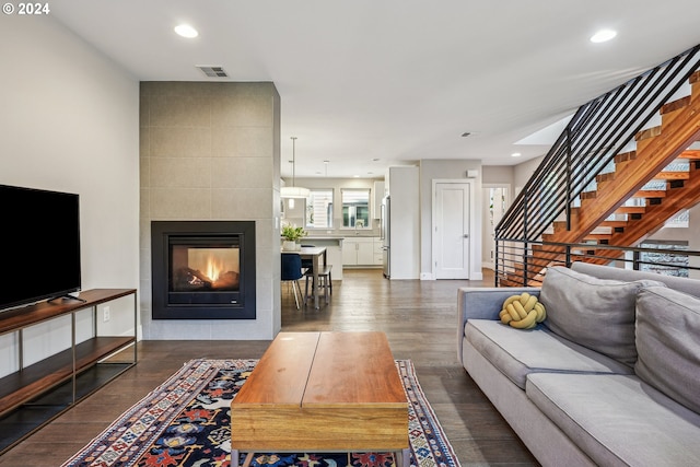 living room with sink, dark hardwood / wood-style flooring, and a tiled fireplace