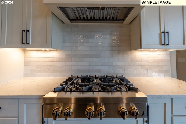 kitchen with ventilation hood, light stone countertops, tasteful backsplash, white cabinetry, and stainless steel gas cooktop