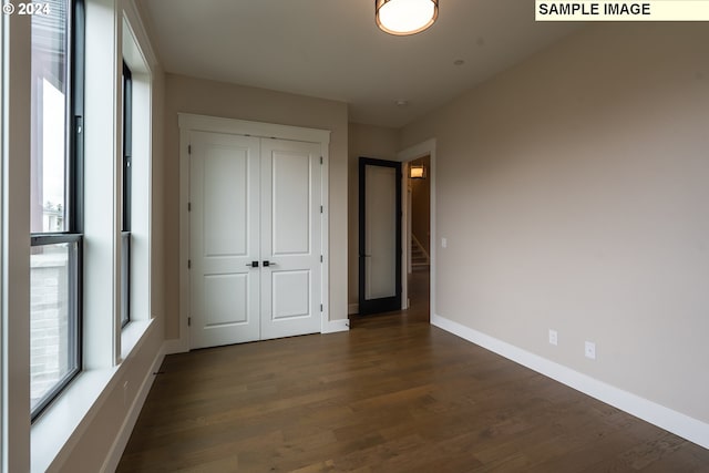 unfurnished bedroom featuring a closet and dark wood-type flooring