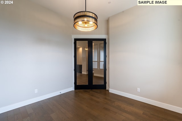 empty room with french doors, dark hardwood / wood-style floors, and a notable chandelier