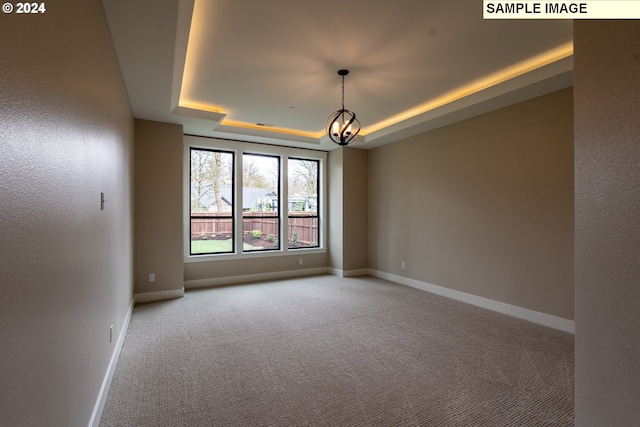 unfurnished room with a chandelier, light carpet, and a tray ceiling