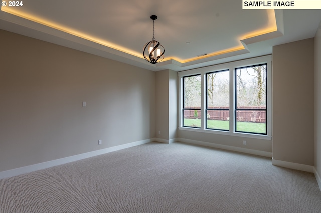 unfurnished room featuring light carpet and a tray ceiling