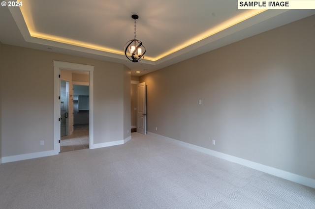 empty room with light carpet and a tray ceiling