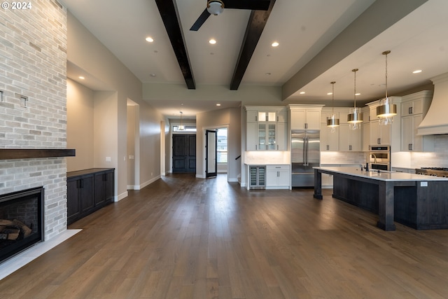 kitchen with dark hardwood / wood-style flooring, a brick fireplace, decorative light fixtures, white cabinets, and built in fridge