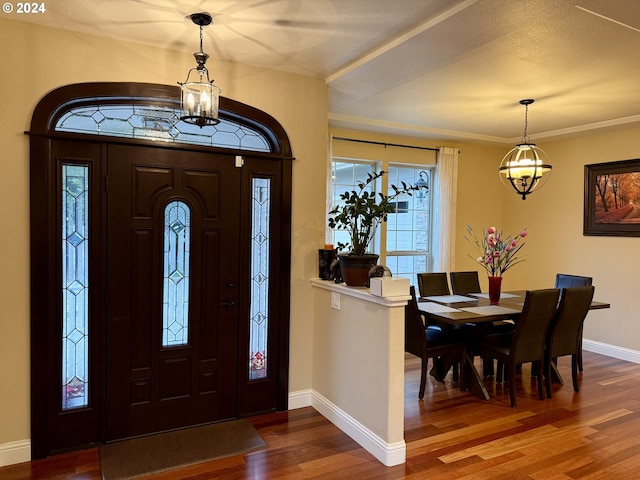 entrance foyer with ornamental molding, a textured ceiling, hardwood / wood-style flooring, and a notable chandelier