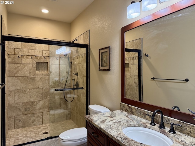 bathroom with vanity, toilet, and a shower with door