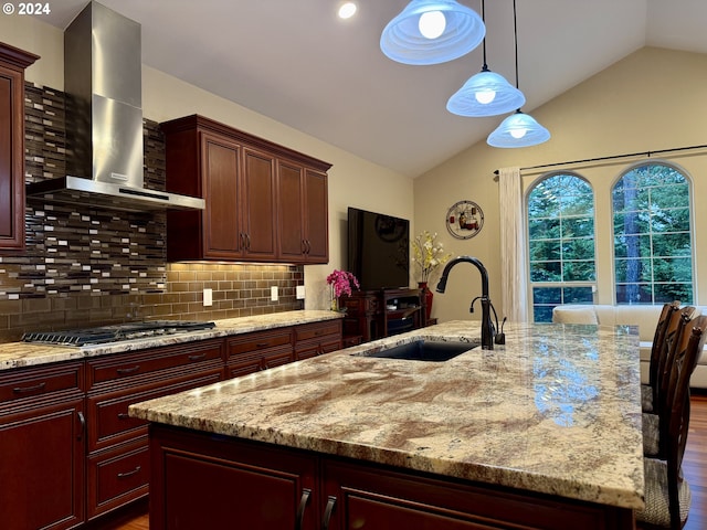 kitchen featuring lofted ceiling, dark hardwood / wood-style flooring, wall chimney range hood, and a center island with sink