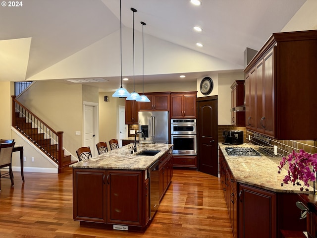 kitchen featuring sink, dark hardwood / wood-style flooring, an island with sink, pendant lighting, and appliances with stainless steel finishes