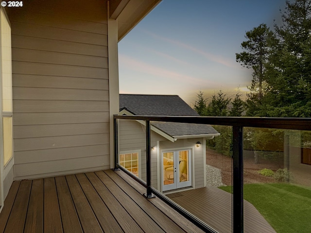 balcony at dusk featuring french doors