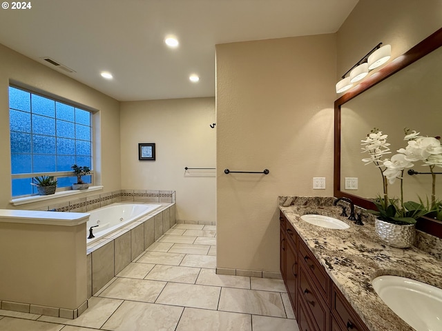 bathroom with tile patterned flooring, vanity, and tiled tub