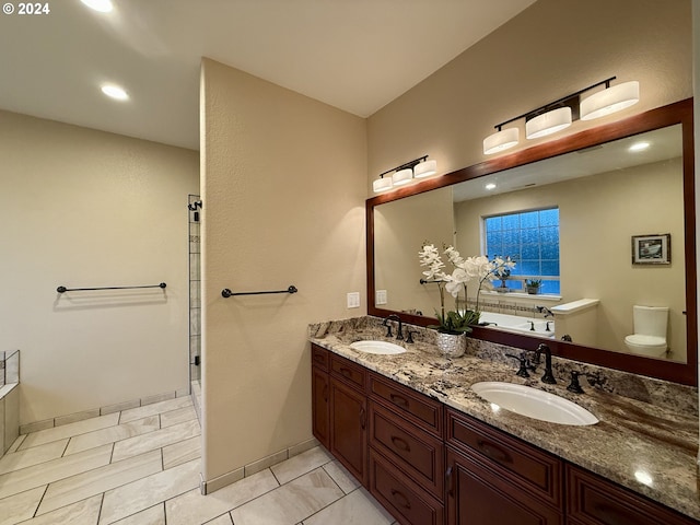 bathroom featuring a washtub, vanity, and toilet