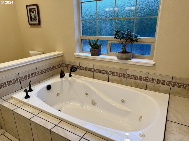 bathroom featuring tiled tub and toilet