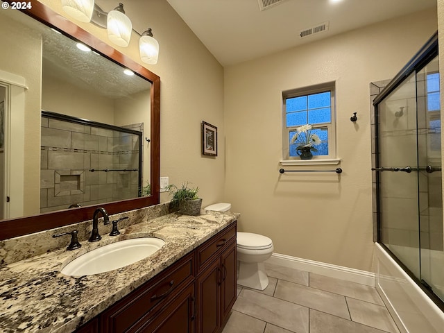 full bathroom featuring tile patterned floors, combined bath / shower with glass door, toilet, and vanity