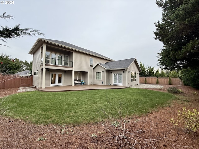 back of property with a lawn, a patio area, french doors, and a balcony