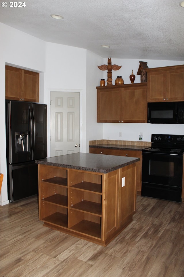 kitchen with hardwood / wood-style flooring, black appliances, a textured ceiling, and a kitchen island