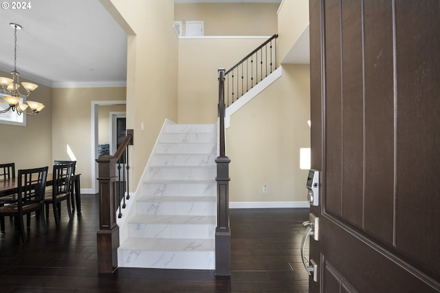 staircase featuring ornamental molding, dark hardwood / wood-style flooring, and a chandelier