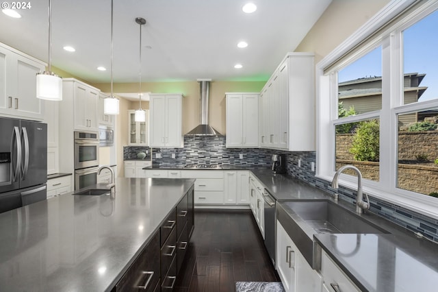 kitchen with white cabinetry, appliances with stainless steel finishes, pendant lighting, and wall chimney exhaust hood