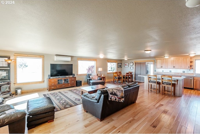 living room featuring a textured ceiling, light wood-style floors, and a wall mounted AC