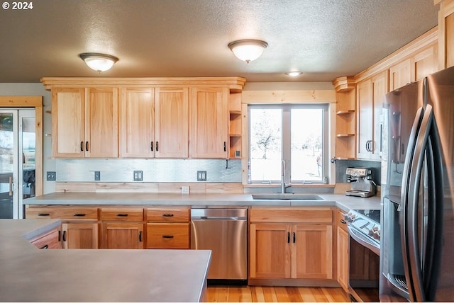 kitchen featuring open shelves, stainless steel appliances, light brown cabinetry, and a sink