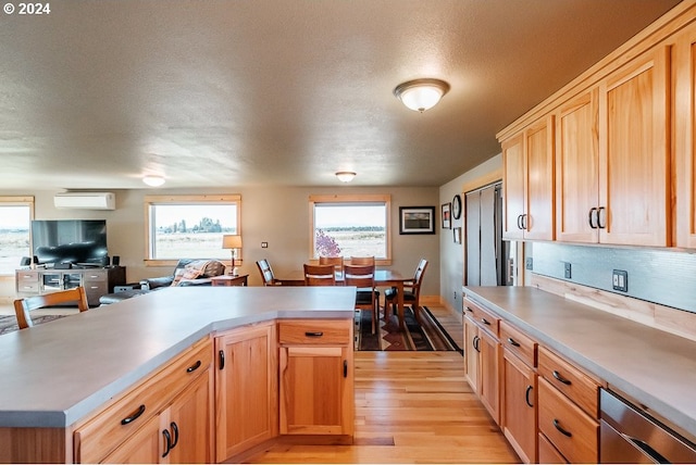 kitchen featuring light wood-type flooring, stainless steel dishwasher, light countertops, and a wall unit AC