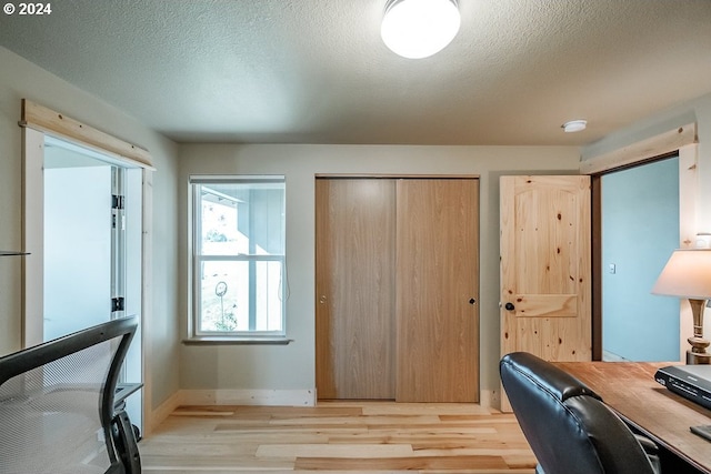 office space featuring baseboards, a textured ceiling, and light wood-style flooring