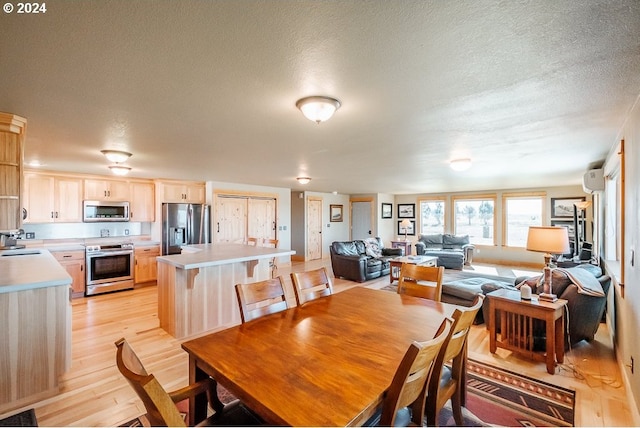 dining room with visible vents, a textured ceiling, a wall mounted AC, and light wood-style floors