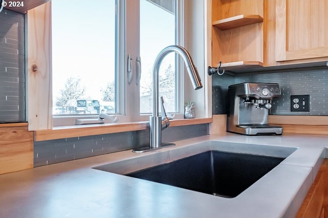 interior details featuring decorative backsplash, light countertops, open shelves, and a sink