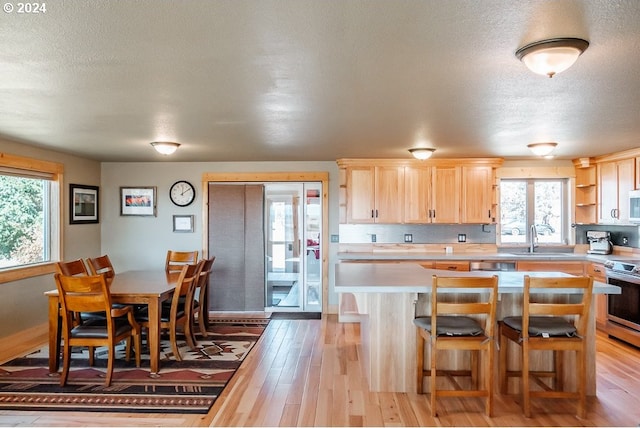 kitchen featuring light wood-style flooring, light brown cabinets, electric stove, a sink, and light countertops