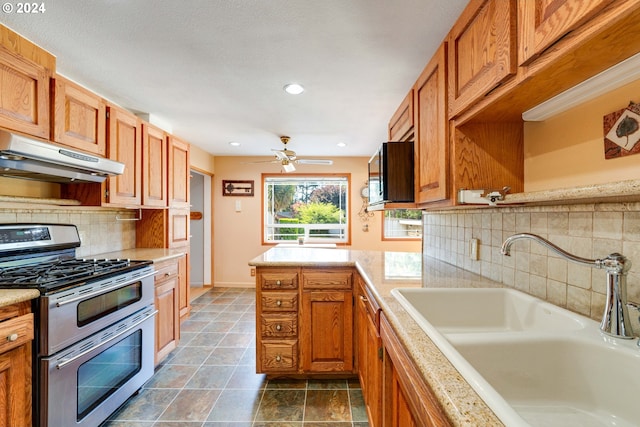 kitchen featuring sink, tasteful backsplash, double oven range, and ceiling fan