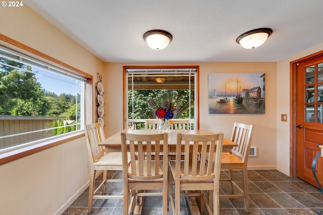 dining room featuring a wealth of natural light, a textured ceiling, and dark tile patterned floors