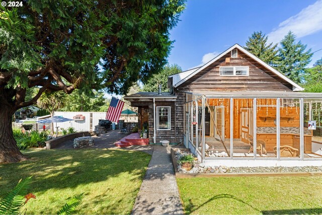 rear view of property featuring a lawn and a sunroom