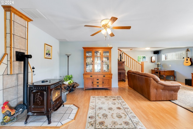 living room featuring ceiling fan, light hardwood / wood-style floors, and a wood stove