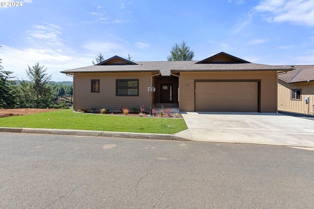 ranch-style home with a garage, a shingled roof, concrete driveway, and a front yard